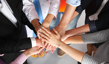 Portrait of people with various occupations putting their hands on top of each other